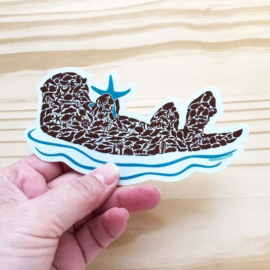 Sea otter vinyl sticker held in hand, featuring unique design, ideal for outdoor use and nature lovers.